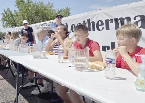 THE ULTIMATE CONTEST FOR HUNGRY KIDS— The Wolf Creek Chapter Daughters of the American Revolution organized this year’s Fourth of July celebration at Leatherman Park. The event brought lots of activities, including a fun run, concerts, dance exhibitions, a farmers market, a car show, giant inflatable balloons and kites, food trucks, and much more, including hot dog and pie eating contests. Pictured are a group of kids trying to pace themselves as they wolf down stacks of hot dogs.