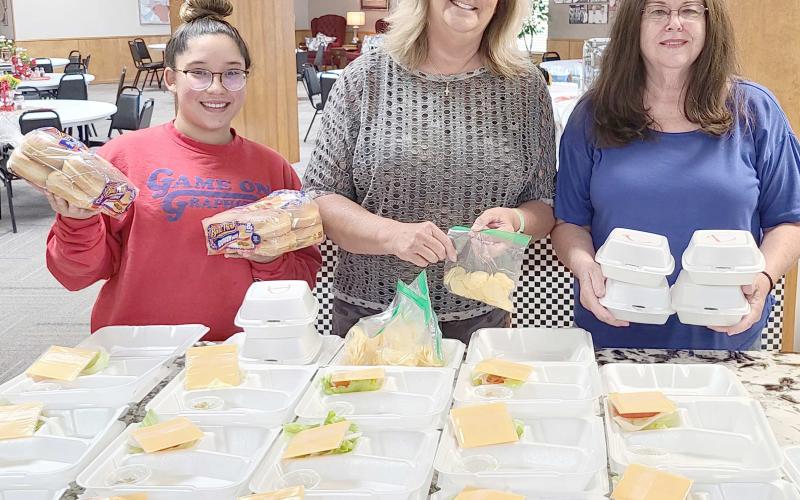 EMERGENCY HAMBURGERS— With natural gas service out across most of the city — and much of their kitchen gas-powered, the Ochiltree County Senior Citizen Center had to make some quick changes last week. So the center’s chefs organized a quick hamburger cookout for last Friday’s lunch. Pictured waiting for the finished hamburger patties to go with all the fixins are, from left, Tahira Gonzalez, Daryla Allred, and Toni Boren.