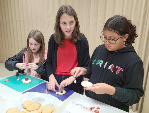 MAKING MUNCHIES—Ochiltree County 4-H members participating in the Fun with Food program got together this week to learn how to bake chocolate chip cookies and fruit pizzas. Pictured assembling their fruit pizzas are, from left, Kendall DeWitt, Brooke Helker, and Allizay Barraza