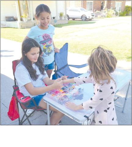 Young entrepreneurs can take many different roads to find success. In the case of Gianna Reyes, age 10, at left, and Brisaedi Garcia, 10, their version of the curbside lemonade stand is more of a bracelet stand — they’ve been creating bracelets for kids, including five-year-old Marissa, who’s getting her new bracelet fitted for size, who come by their table at 1010 S. Drake.