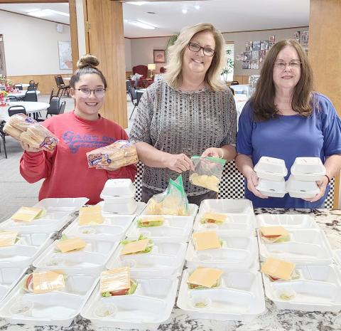 EMERGENCY HAMBURGERS— With natural gas service out across most of the city — and much of their kitchen gas-powered, the Ochiltree County Senior Citizen Center had to make some quick changes last week. So the center’s chefs organized a quick hamburger cookout for last Friday’s lunch. Pictured waiting for the finished hamburger patties to go with all the fixins are, from left, Tahira Gonzalez, Daryla Allred, and Toni Boren.
