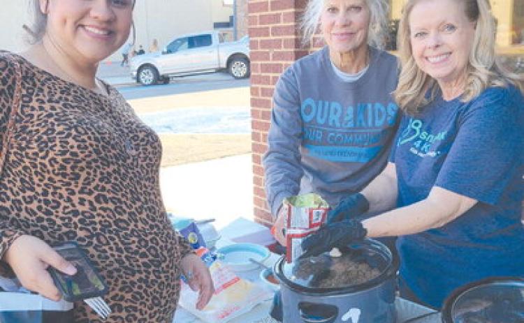 DINNER ON THE RUN— Perryton residents looking for sales, entertainment, and fun snacks visited downtown Perryton on Thursday evening for the annual Moonlight Madness event sponsored by the Perryton Ochiltree Chamber of Commerce. Pictured at the Snack Pak 4 Kids booth are, from left, Ruth Romero waiting for a walking taco from Snack Pak volunteers Carol Hayden and Becky Childers.