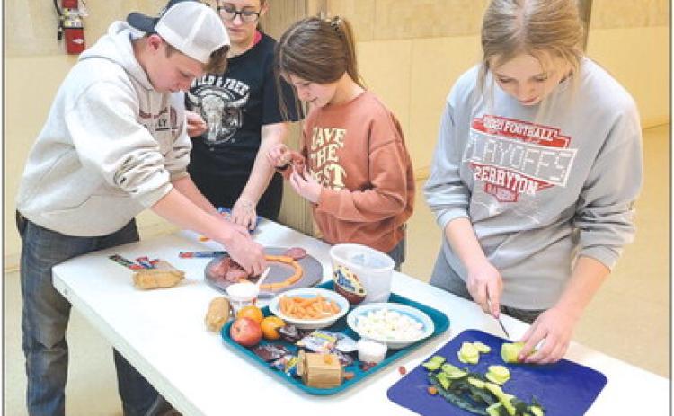 Members in Ochiltree County 4H’s Alamo Club tested their culinary skills last week on Monday as they worked to assemble snack boards, featuring meat, cheese, fruits, crackers, and candies. Pictured are, from left, Kyle Oquin, Emmalyn Overton, Hallie Lopez, and Emmalee Lopez.